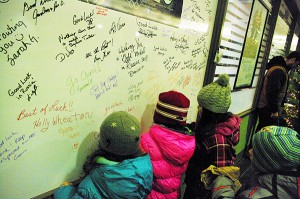 Youngsters sign a well-wishing card for Gord McArthur following Friday's Santa Claus Parade. Carrie Schafer/e-KNOW