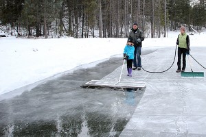 Tom, Sarah and Julie use the home made 'Zamboni' to put a thin layer of water on the ice.